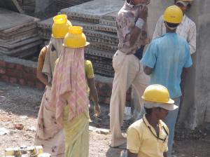 LOOK AT THE HELMETS WORN BY THE FEMALE WORKERS. HELMET HAS A SPECIAL PROVISION TO SECURE THE BUCKET ON IT.